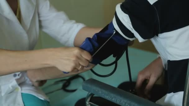 Werknemer van de kliniek brengen bloeddruk manchet op de arm van de patiënt, bloeddrukmeter — Stockvideo