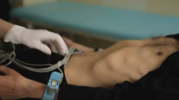 Медсестра, закрепляющая электроды на конечностях пациентов для кардиологических тестов, оборудование — стоковое видео