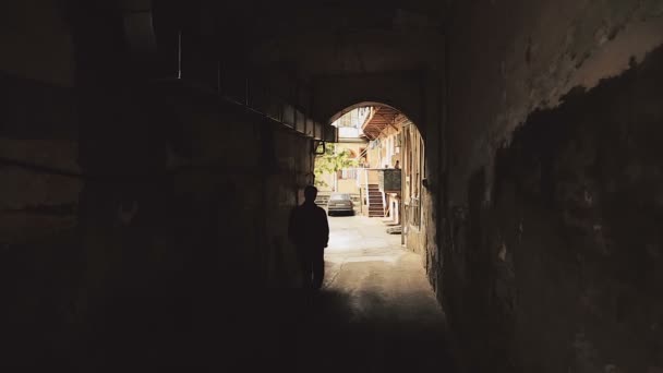 Unidentified silhouette of strange man walking through dark alleys in city — Stock Video