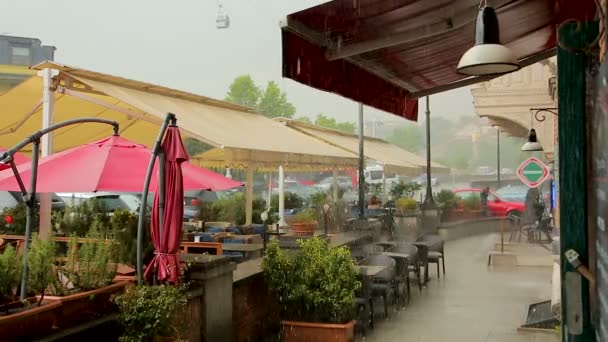 Tabellen van de gezellige straat café steeds nat in de stromende regen, klimaat van Georgië — Stockvideo