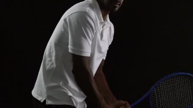 Beyaz polo siyah arka plan, yavaş topa vurmak içinde kas tenis oyuncusu