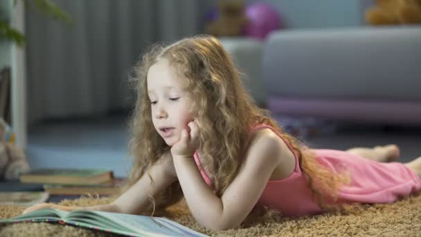 Smart little girl reading favorite book at home on her own, happy childhood — Stock Video