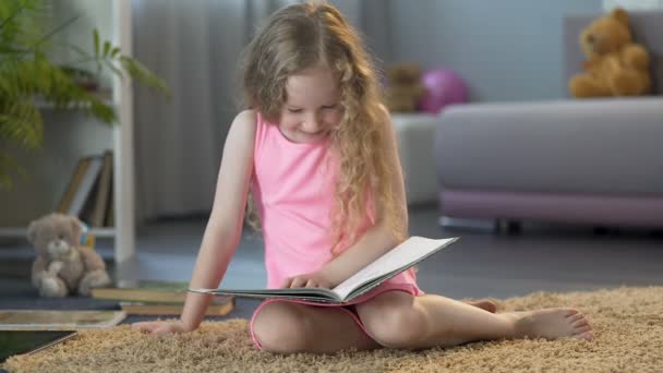 Pequeño niño leyendo, riéndose de la historia divertida en el libro de los niños, educación temprana — Vídeos de Stock