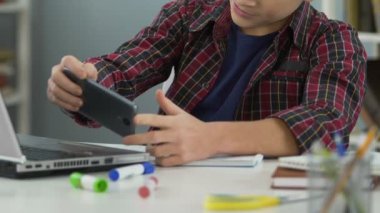 Tembel erkek genç ödev yapmak yerine smartphone cep telefonu ile mobil oyun oynuyor