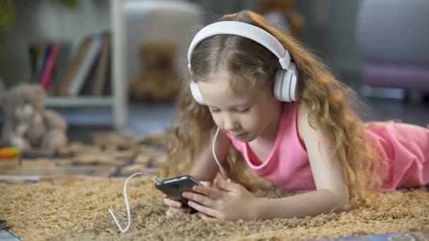 Aranyos lány felszívódik, a virtuális világban, játékok és zene-apps, smartphone — Stock videók
