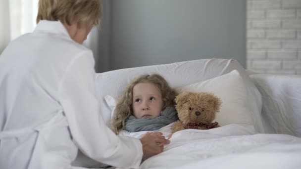 Ärztin hält krankes Mädchen an der Hand und spricht mit ihr, Behandlung zu Hause — Stockvideo