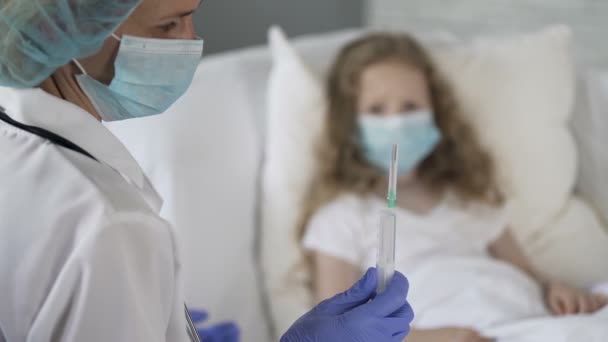 Unhappy scared child in medical face mask looking at nurse with syringe in hand — Stock Video