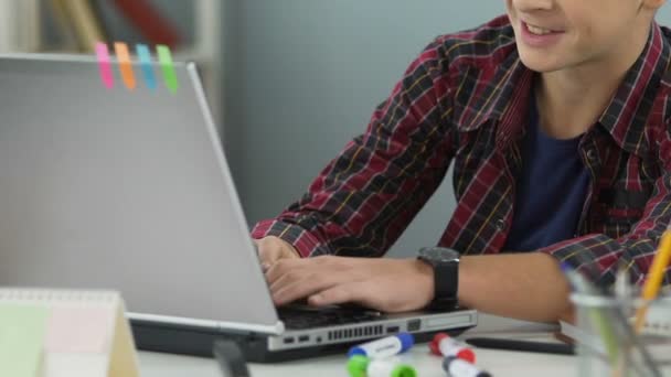 Adolescente sonriendo y escribiendo en el ordenador portátil, haciendo la tarea, el lugar de trabajo del estudiante — Vídeos de Stock