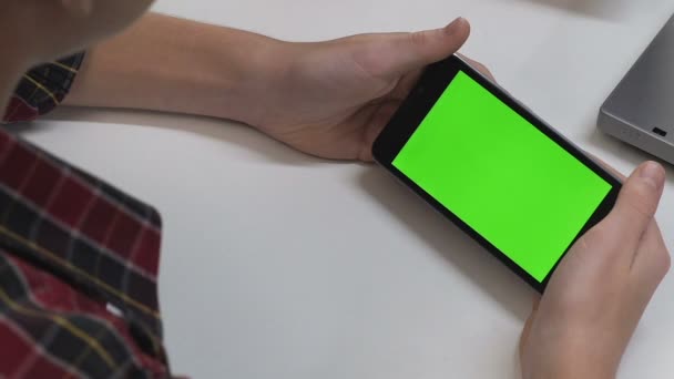 Teenager sehen Film auf dem Smartphone zu Hause Tisch, Freizeit, grüner Bildschirm — Stockvideo