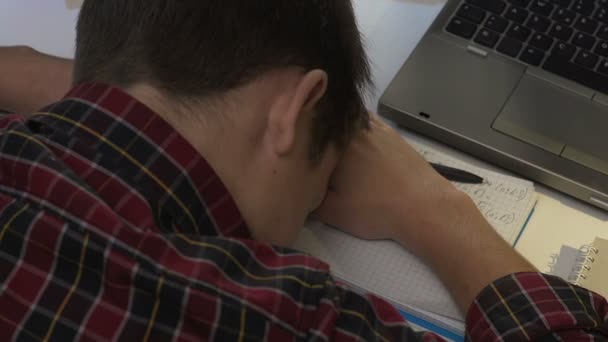 Fáradt fiú elaludt, miközben csinál házi feladatot a könyvek tábla és a laptop, a fáradtság — Stock videók