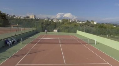Adam açık havada, mahkeme ve dağ evleri ile görünümünü şaşırtıcı tenis oynamaya