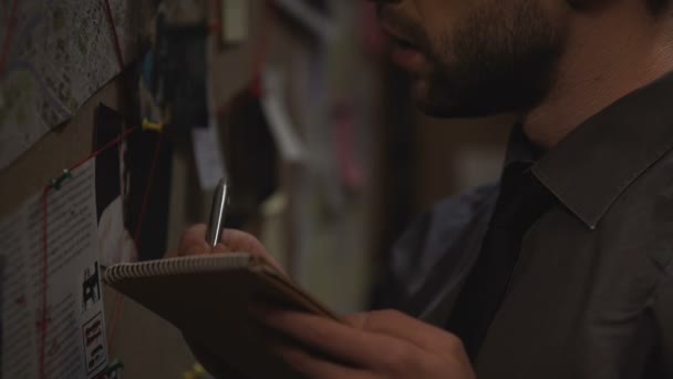 Χαριτωμένο μπάτσος γράφοντας τις σκέψεις σε ποινική υπόθεση στο σημειωματάριο, συστηματοποιεί πληροφορίες — Αρχείο Βίντεο