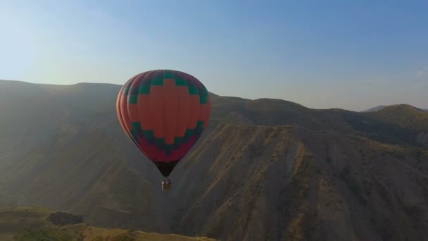 Vista panorámica del globo aerostático volando a través del cielo en el paisaje montañoso — Vídeos de Stock