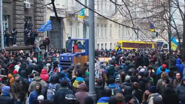 КИЕВ, УКРАИНА - ДЕКАБРЬ CIRCA 2014: демонстрации Евромайдана. Большой синий и желтый бульдозер движется назад в середине украинских протестующих — стоковое видео