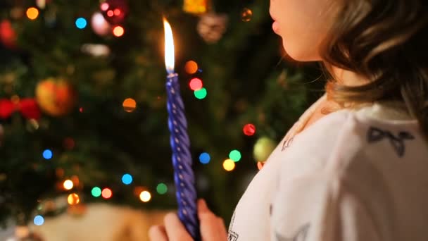 Eenzame tiener kaars houden en het maken van een wens in de buurt van ingerichte fir tree — Stockvideo