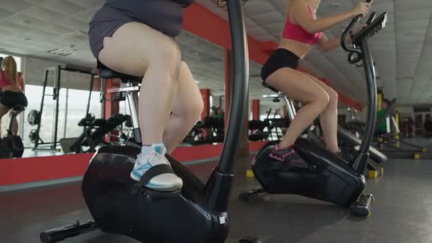 Ноги ожиріння жіночої педалі повільно на тренувальному велосипеді у фітнес-клубі — стокове відео