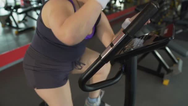 Mujer regordeta trabajando duro en bicicleta estacionaria en el club deportivo, fitness corporal — Vídeos de Stock