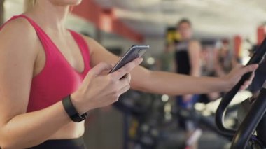 Kadın, sabit bisiklet sürme ve mesafe telefon izleme bileklik