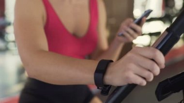 Fitness becerikli, ince kadın ile spor salonunda üzerinde sabit bisiklet sürme bileklik