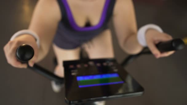 Mujer obesa montando bicicleta estacionaria y mirando el panel electrónico, deporte — Vídeo de stock