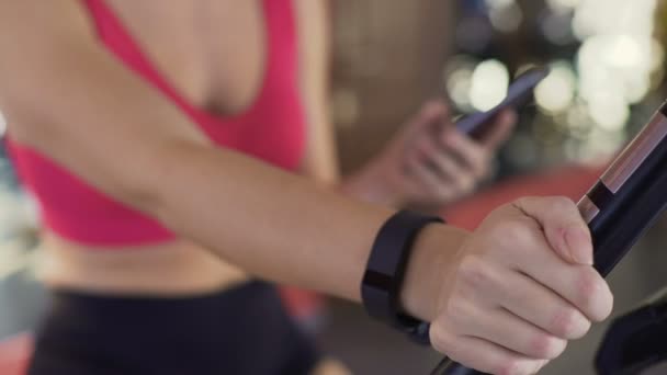 Pulsera de fitness en la mano de las mujeres, chica atlética montar bicicleta estática, primer plano — Vídeos de Stock