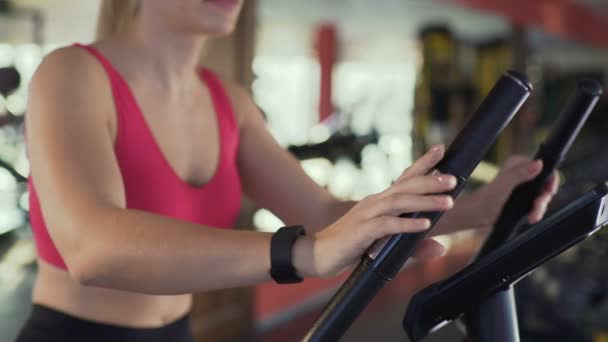 Chica deportiva montar bicicleta estática y la distancia de monitoreo en pulsera de fitness — Vídeo de stock
