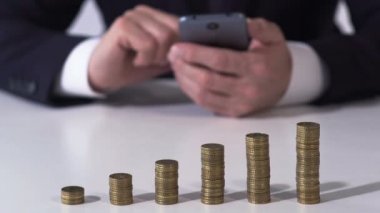 Erkek bankacı smartphone ile para kazık tablo, üzerinde para birimi oranı kontrol