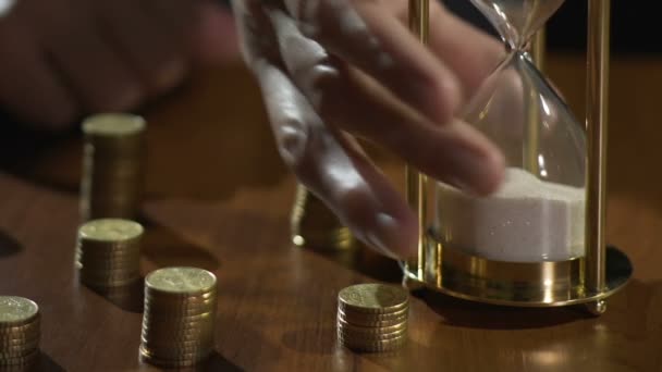 Soustružení přesýpací hodiny, hromady mincí na stůl, ruce investičního období — Stock video