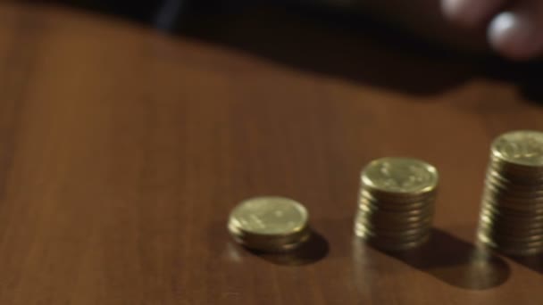 Vista de crecientes pilas de monedas en fila sobre la mesa con arena fluyendo en reloj de arena — Vídeo de stock