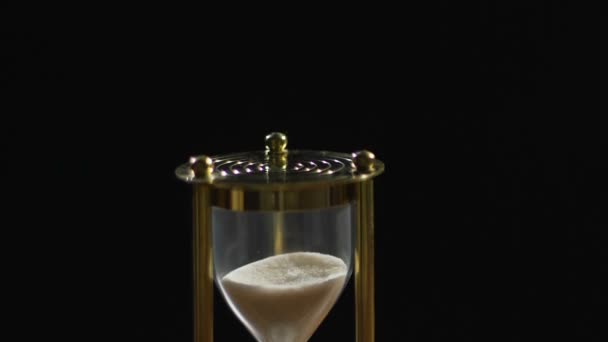 Zand stroomt in gouden zandloper op tafel, met tijd concept, minuten passeren — Stockvideo