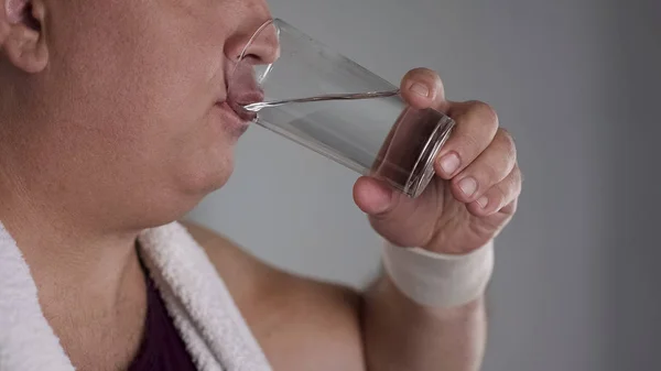 Nahaufnahme eines molligen Mannes, der frisches Wasser aus dem Glas trinkt, gesunde Diät zur Gewichtsabnahme — Stockfoto