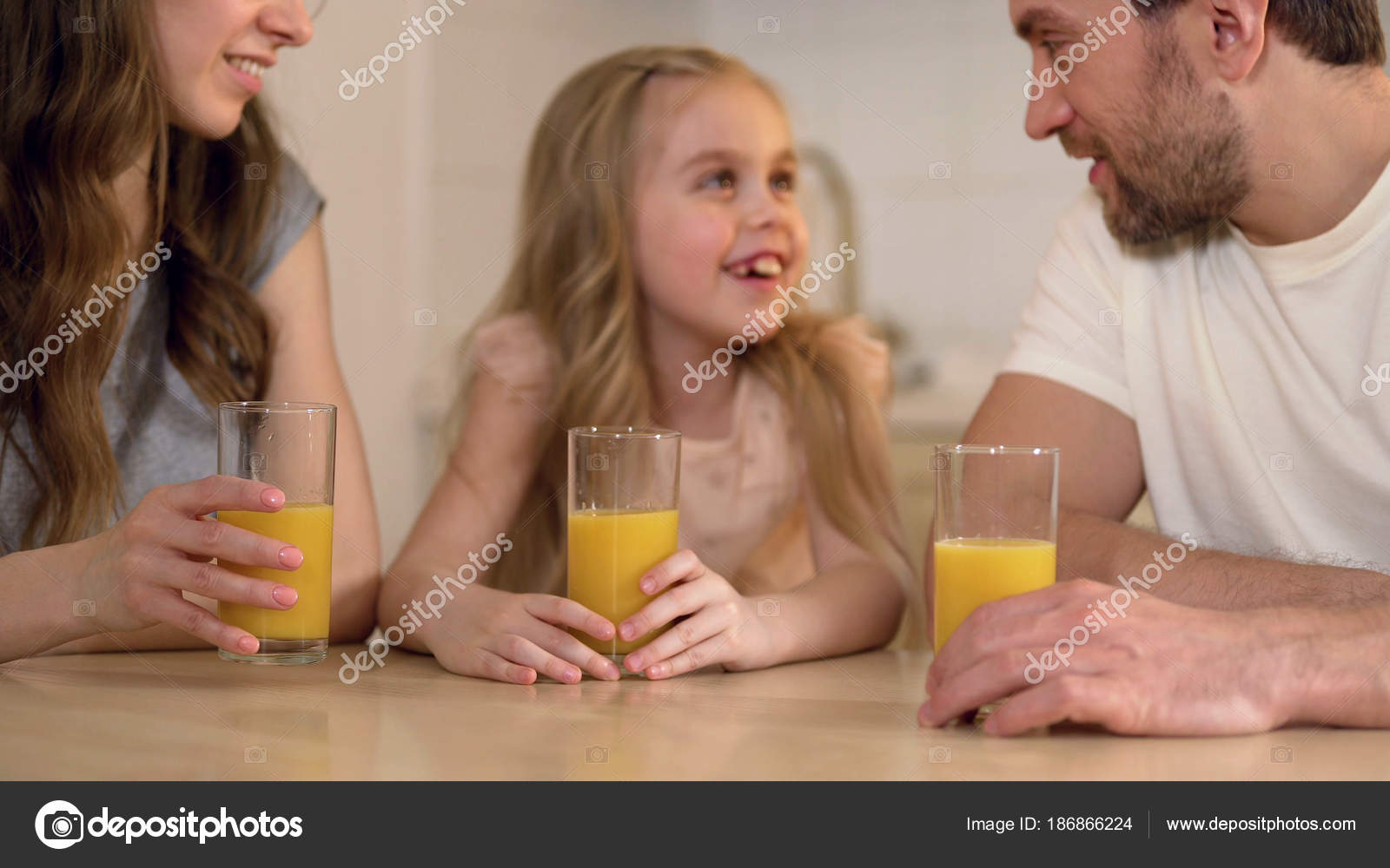 Parents telling little daughter about vitamins in orange juice, morning at home — Stock Photo