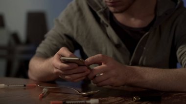 Uyuşturucu bağımlısı metinler üzerinde Smartphone-e doğru satıcı, ihtiyacı olan doz, kullanılan enjektörler yalan çevresinde