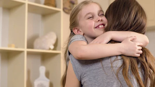 Щаслива маленька дівчинка посміхається і обіймає матір з любов'ю, теплими дитячими спогадами — стокове фото