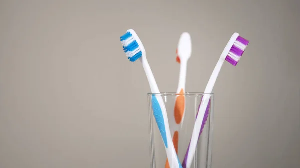 Three colored toothbrushes stand on shelf in bathroom, care for oral cavity — Stock Photo, Image