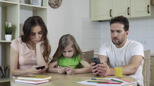 Батько, мати і дочка використовують гаджети вдома, відсутність живого спілкування — стокове фото