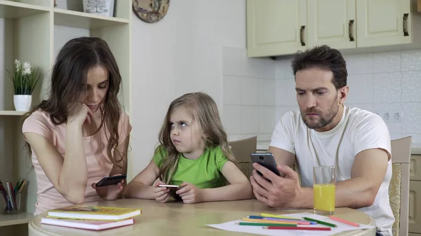 Man and woman focused on smartphones, little daughter needs parents attention — Stock Photo, Image