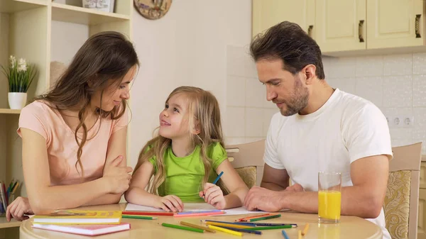 Chica haciendo dibujos, mirando a los padres con amor, disfrutando del ocio juntos — Foto de Stock