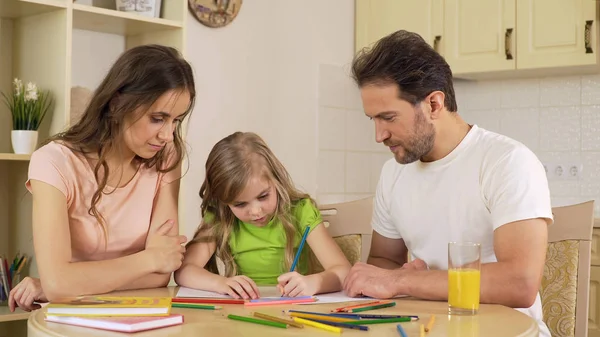 Дружня сім'я сидить на кухні малюючи фотографії, насолоджуючись дозвіллям разом — стокове фото