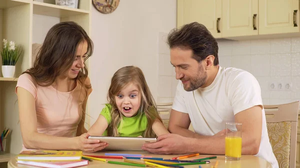 Parents showing daughter app on tablet, excited girl shocked and surprised — Stock Photo, Image