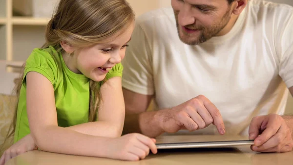Szczęśliwy ojciec i córka korzystających śmieszne aplikacja edukacyjna na komputerze typu tablet — Zdjęcie stockowe