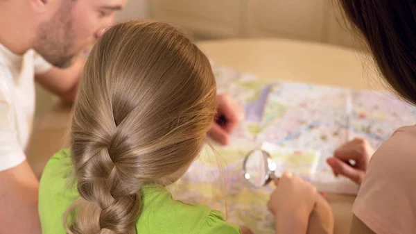 Батьки і дочка дивляться на мапу, планують місце для літніх канікул — стокове фото