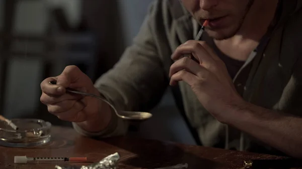 Junkie mantém a dose de heroína na colher e prepara a seringa para injeção, de perto — Fotografia de Stock
