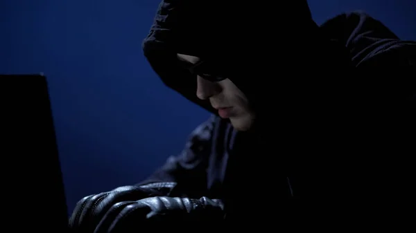 Homem estranho em roupas pretas, óculos escuros e luvas roubando dados do laptop — Fotografia de Stock