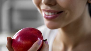 Genç bir kadın tutarak taze kırmızı elma egzersiz yaptıktan sonra düşük kalorili meyve gülümseyen
