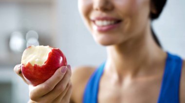 Girl holding bite apple replenishing her body with vitamins, healthy teeth clipart