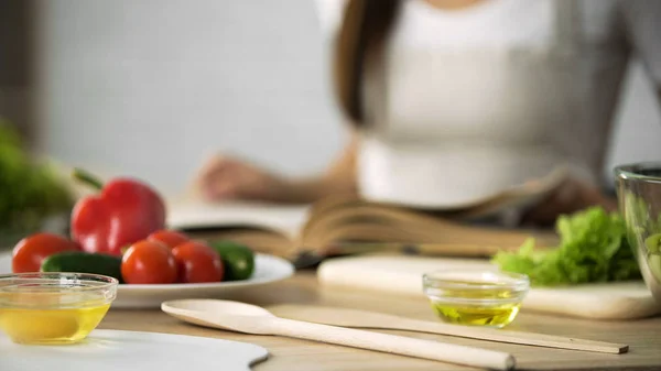 Close-up of girl flipping through cooking book pages, choosing salad recipe — Stock Photo, Image