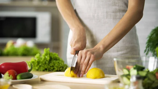 Female chef cutting lemon with sharp knife for lunch preparing, cooking tips — Stock Photo, Image