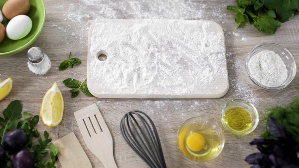 Kitchen board med bakning mjöl på bordet och bakverk ingredienser runt — Stockfoto