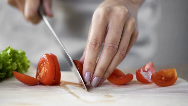 Female culinary expert cutting tomato vegetables on the table in restaurant — Stock Photo, Image